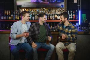 Friends resting in the pub with beer in hands. Having conversation. photo