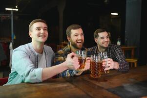 Soccer fans at the bar. Happy football fans cheering at bar and drinking beer while bartender serving beer at the background photo