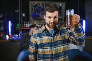 Handsome bearded man drinking beer at the bar counter in pub photo