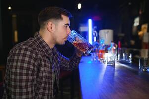 Night in bar. Portrait of cheerful men drinking beer at the bar photo