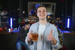 Handsome bearded man drinking beer at the bar counter in pub photo