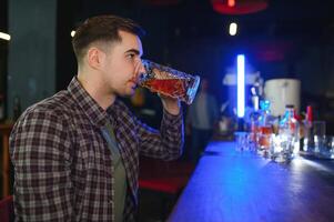 Night in bar. Portrait of cheerful men drinking beer at the bar photo