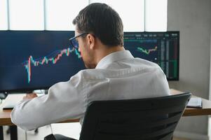 Successful trader in formalwear checking cryptocurrency information data on finance market graph, working in office photo