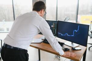Successful trader in formalwear checking cryptocurrency information data on finance market graph, working in office photo