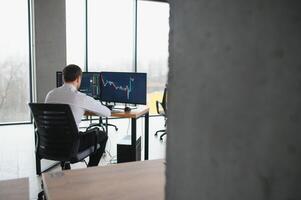Serious business man trader analyst looking at computer monitor, investor broker analyzing indexes, financial chart trading online investment data on cryptocurrency stock market graph on pc screen. photo