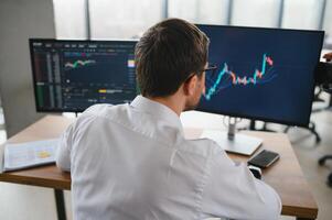Successful trader in formalwear checking cryptocurrency information data on finance market graph, working in office photo
