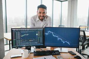 Portrait of a positive successful Indian or Arabian trader, stock market broker, Crypto charts on laptop screen photo