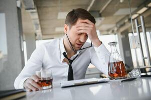 Alcoholism at work. Tired employee drinking alcohol at workplace, can not handle stress. photo