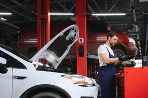 Portrait Shot of a Handsome Mechanic Working on a Vehicle in a Car Service. Modern Clean Workshop. photo