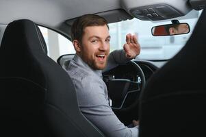 Taxi driver smiling while turning over to the backseat looking talking with clients. Successful businessman husband looking at the backseat at dealer shop before buying a car photo