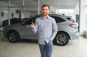 Yes, that's my new car. Customer in car dealership. Young man with keys in hand. photo