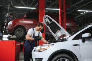 Portrait Shot of a Handsome Mechanic Working on a Vehicle in a Car Service. Modern Clean Workshop. photo