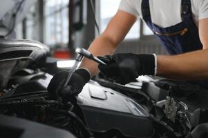 Portrait Shot of a Handsome Mechanic Working on a Vehicle in a Car Service. Modern Clean Workshop. photo