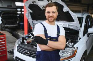 Portrait Shot of a Handsome Mechanic Working on a Vehicle in a Car Service. Modern Clean Workshop. photo