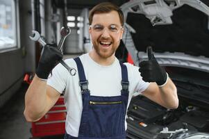 Portrait Shot of a Handsome Mechanic Working on a Vehicle in a Car Service. Modern Clean Workshop. photo