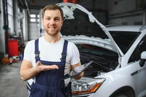 Automobile computer diagnosis. Car mechanic repairer looks for engine failure on diagnostics equipment in vehicle service workshop photo