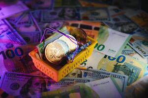 Close up heap of golden bitcoin physical coins on top of Euro, dollar banknotes background, high angle view, selective focus photo