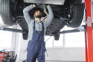 Auto mechanic working underneath a lifted car photo