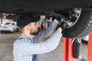 Portrait of a mechanic repairing a lifted car photo
