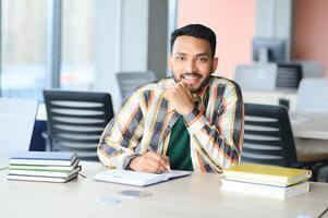 Handsome young Indian boy student with books and backpack at university. Education concept photo