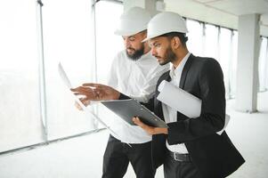 Multiracial male coworkers in hardhats discussing project on construction site photo