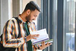 Handsome young Indian boy student with books and backpack at university. Education concept photo