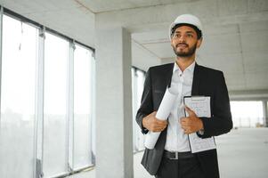 architecture, construction business and building concept - happy smiling indian male architect in helmet. photo
