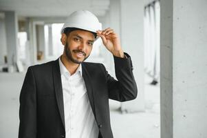 architecture, construction business and building concept - happy smiling indian male architect in helmet. photo