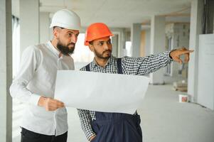 contento trabajadores a construcción sitio, joven civil ingeniero gerente y arquitectos indio y árabe ingenieros foto