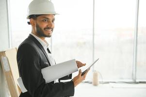 Asian engineer handsome man or architect with white safety helmet in construction site. Standing at modern building construction. Worker asian man working project building photo
