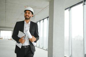 Asian engineer handsome man or architect with white safety helmet in construction site. Standing at modern building construction. Worker asian man working project building photo