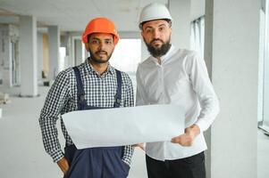 contento trabajadores a construcción sitio, joven civil ingeniero gerente y arquitectos indio y árabe ingenieros foto