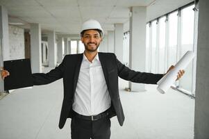 Asian engineer handsome man or architect with white safety helmet in construction site. Standing at modern building construction. Worker asian man working project building photo