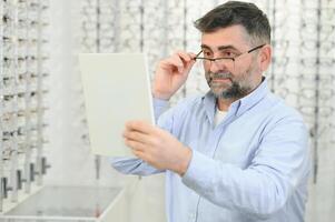 Glasses check, senior vision and elderly man at a consulting optometry clinic for wellness. Happy, smile and old face with lens, frame and eyewear choice in a store for help getting a prescription. photo