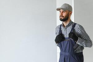 Portrait of handsome mechanic with stubble in blue overall, shirt having his arms crossed, looking at camera photo