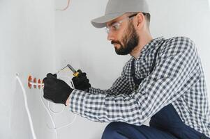 electrician installs socket boxes on the wall and puts a putty on them photo