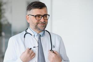 Portrait of serious senior doctor in eyeglasses and in white coat. photo