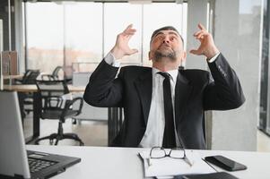 Angry businessman sitting at the table and screaming over. photo