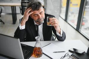 Old business man is drinking alchool at the office photo