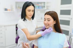 Image of pretty young woman sitting in dental chair at medical center while professional doctor fixing her teeth photo