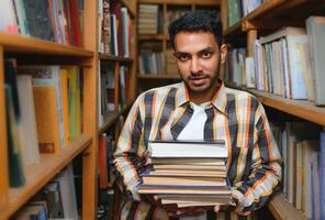 Male indian student at the library with book photo