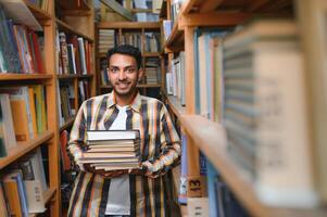 Male indian student at the library with book photo