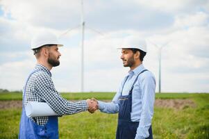 Two engineers discussing against turbines on wind turbine farm. photo