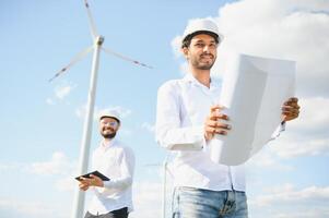 Two engineers discussing against turbines on wind turbine farm. photo