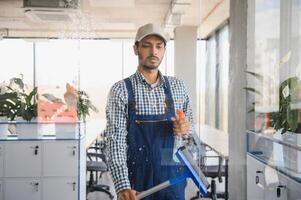Male janitor cleaning window in office photo