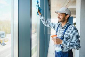 Male janitor cleaning window in office photo