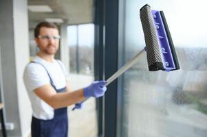 Young man washing window in office photo