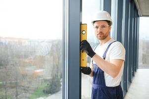 Worker using bubble level after plastic window installation indoors photo