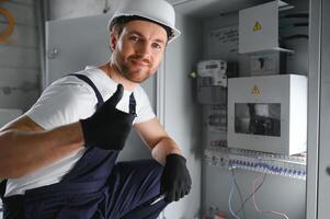 Man, an electrical technician working in a switchboard with fuses. Installation and connection of electrical equipment. Professional with tools in hand. concept of complex work, space for text. photo