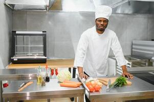 Portrait of happy African American male chef standing in restaurant kitchen photo
